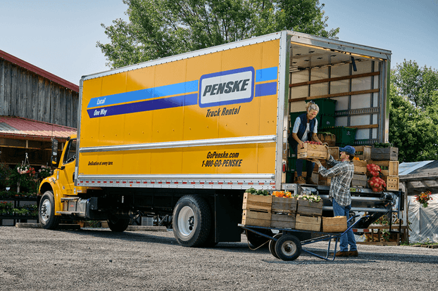 People unloading vegetables from a yellow Penske rental truck