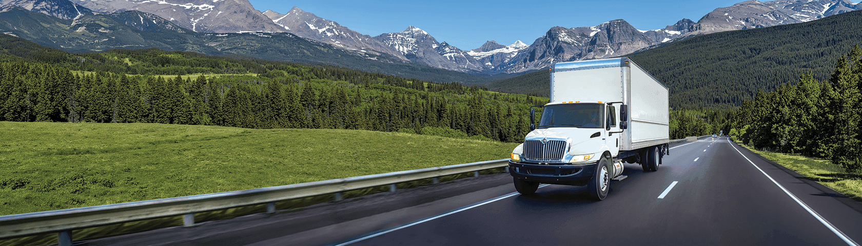 White  Penske box truck on the highway with mountains in the background
